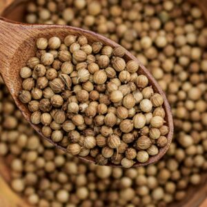 Detailed view of coriander seeds in a wooden spoon, emphasizing texture.