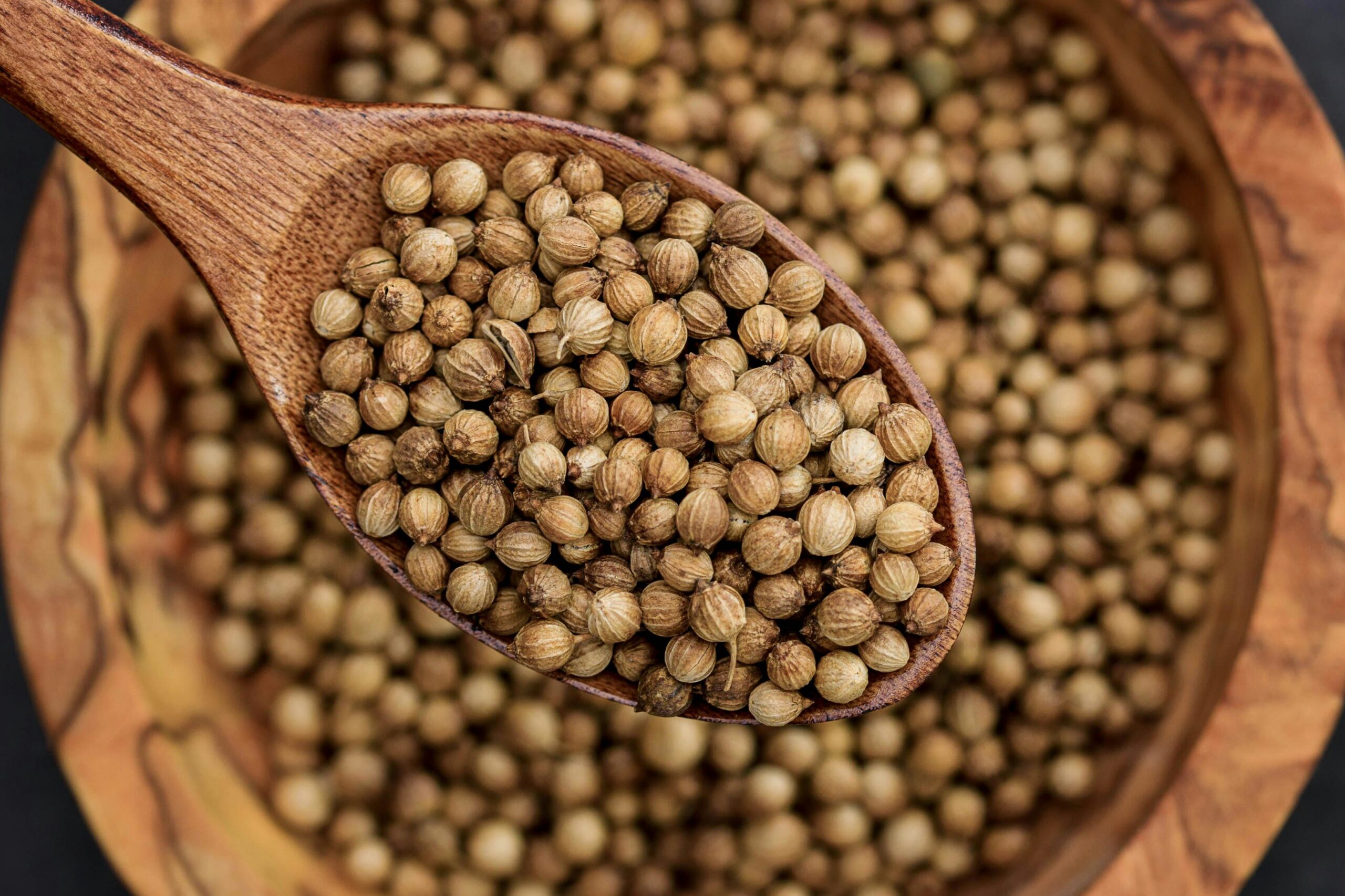 pexels photo 10487771 10487771 Detailed view of coriander seeds in a wooden spoon, emphasizing texture.